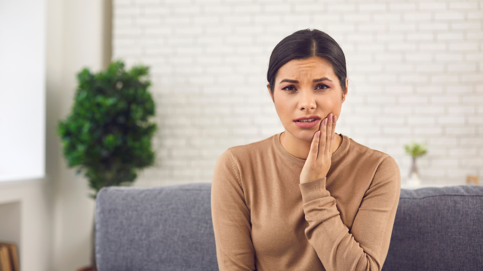 An image of a woman in a brown dress suffering from tooth pain.