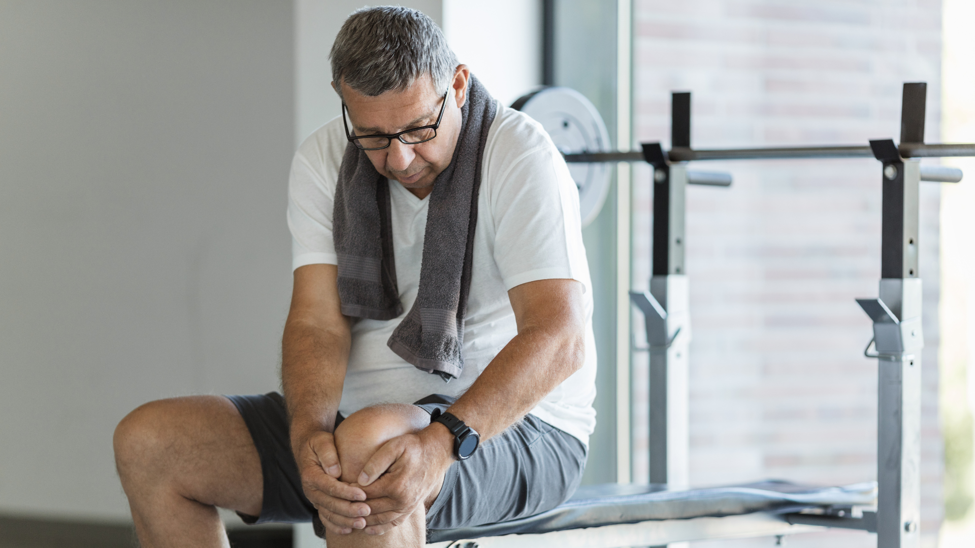 An image of an elderly man at the gym suffering from knee pain.